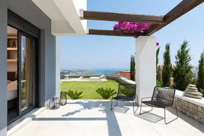 a patio with two chairs and a view of a yard at Villa La Bianca in Koskinou
