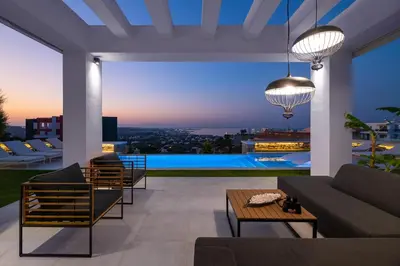 a living room with a view of the city at night at Villa La Bianca in Koskinou