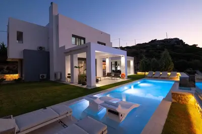 a villa with a swimming pool in front of a house at Villa La Bianca in Koskinou