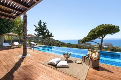 a swimming pool with a wooden deck and the ocean at Villa Equinox in Ixia