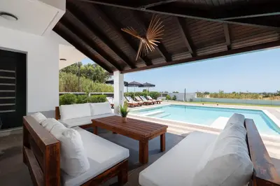 an outdoor patio with a pool and a table and chairs at Elysian Villa in Afantou