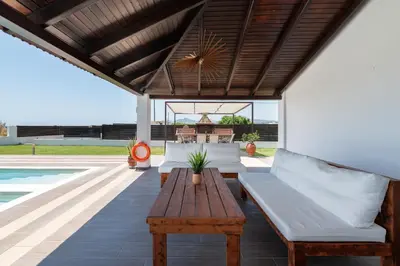 an outdoor patio with a wooden table and a bench at Elysian Villa in Afantou