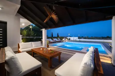 a villa with a swimming pool at night at Elysian Villa in Afantou