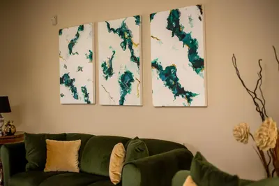 a living room with a green couch and three paintings on the wall at Villa de Manu in Rhodes Town
