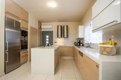 a kitchen with wooden cabinets and stainless steel appliances at Villa de Manu in Rhodes Town