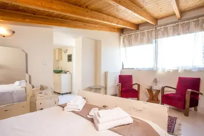 a bedroom with a bed and two red chairs at Villa de Manu in Rhodes Town