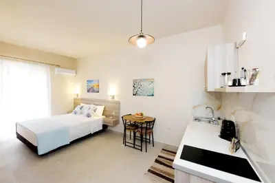 a bedroom with a bed and a kitchen with a table at Venus Island Studios in Líndos