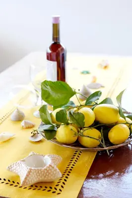 a plate of lemons on a table with a bottle of wine at Venus Island Studios in Líndos