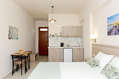 a bedroom with a bed and a table and a kitchen at Venus Island Studios in Líndos