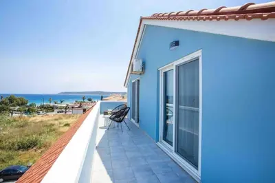 a blue house with a balcony with a view of the ocean at MEGAT SEAVIEW AND SEASIDE APARTMENTs in Ialyssos