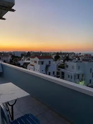 a view of a city from a balcony at sunset at MEGAT SEAVIEW AND SEASIDE APARTMENTs in Ialyssos