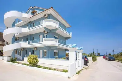 a blue building with white balconies on a street at MEGAT SEAVIEW AND SEASIDE APARTMENTs in Ialyssos