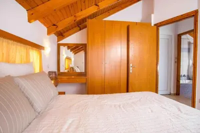 a bedroom with a large bed and a wooden cabinet at MEGAT SEAVIEW AND SEASIDE APARTMENTs in Ialyssos