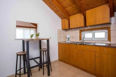 a kitchen with wooden cabinets and a sink and stools at MEGAT SEAVIEW AND SEASIDE APARTMENTs in Ialyssos