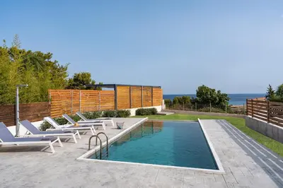 a swimming pool with chaise lounge chairs next to a swimming pool at Luxury NissoVilla with Private Pool & Sea Views in Kolimbia