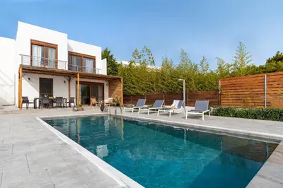 a swimming pool with chairs and a house at Luxury NissoVilla with Private Pool & Sea Views in Kolimbia