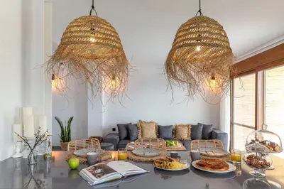 a living room with two chandeliers and a table with food at Luxury NissoVilla with Private Pool & Sea Views in Kolimbia