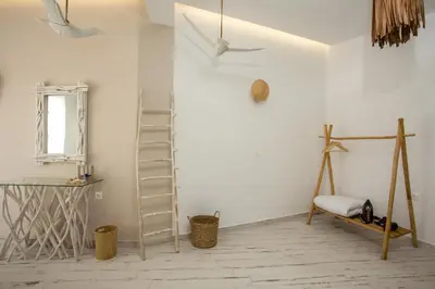 a room with a white wall with a ladder and a chair at Marini Seaside in Faliraki