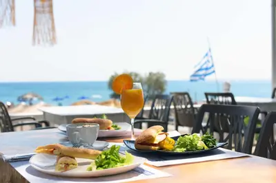 a table with plates of food and a glass of orange juice at Marini Seaside in Faliraki