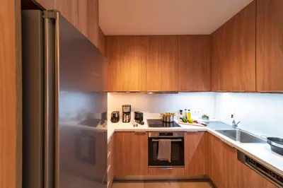a kitchen with wooden cabinets and a stainless steel refrigerator at Lucian City Apartments in Rhodes Town