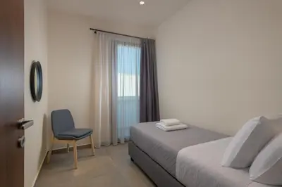 a bedroom with a bed and a chair and a window at Lucian City Apartments in Rhodes Town