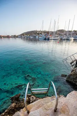 a bench in the water with boats in a marina at Villa Phaedra in Halki
