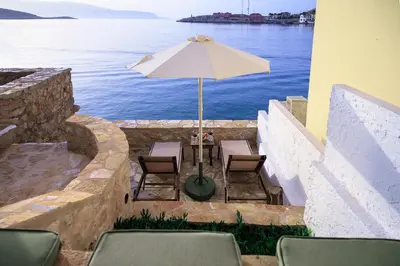 a table and chairs with an umbrella and the water at Villa Phaedra in Halki