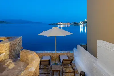 a table and chairs with an umbrella in front of the water at Villa Phaedra in Halki