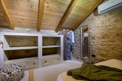 a bedroom with a bed and a stone wall at Villa Phaedra in Halki