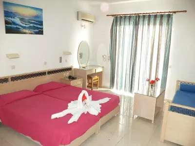 a bedroom with a large red bed with a white flower on it at White Palace Pavlos apartment1 in Faliraki