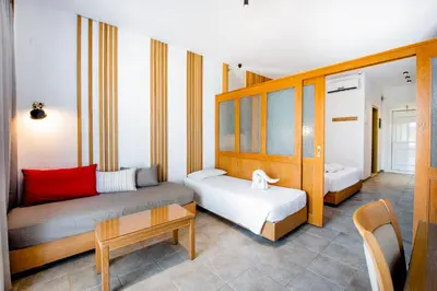 a room with two beds and a table in a room at Lindos View Hotel in Líndos
