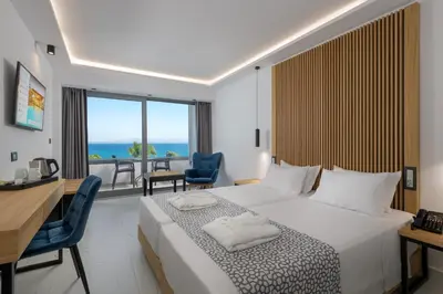 a hotel room with a bed and a desk and chairs at Oceanis Beach Hotel in Ixia