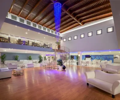 a large lobby with white couches and a staircase at Oceanis Beach Hotel in Ixia