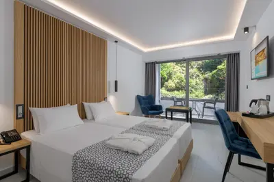 a hotel room with a bed and a table and chairs at Oceanis Beach Hotel in Ixia