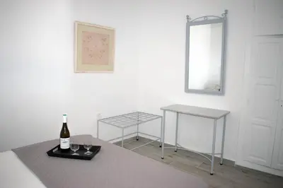 a white room with a bottle of wine and two tables at Marea Apartments in Symi