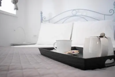 a tray with two cups and a plate on a bed at Marea Apartments in Symi