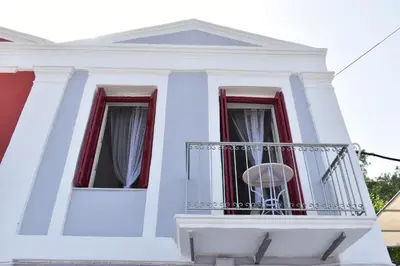 a white house with a balcony with a chair on it at Marea Apartments in Symi