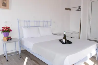 a white bed with a bottle of wine on a tray at Marea Apartments in Symi