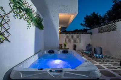 a jacuzzi tub on a patio with two chairs at CASA MIKELE by Sarikas - SEA SIDE SUITES and STUDIOS -adults only in Faliraki