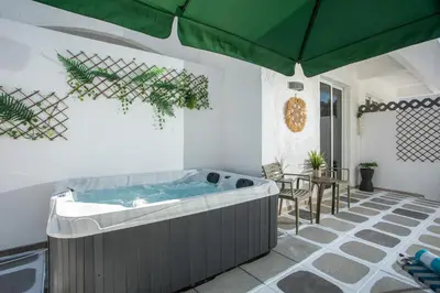 a hot tub in a patio with a green umbrella at CASA MIKELE by Sarikas - SEA SIDE SUITES and STUDIOS -adults only in Faliraki