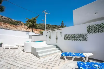 a patio with white walls and stairs and blue chairs at CASA MIKELE by Sarikas - SEA SIDE SUITES and STUDIOS -adults only in Faliraki