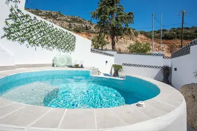 a swimming pool with blue water in a white house at CASA MIKELE by Sarikas - SEA SIDE SUITES and STUDIOS -adults only in Faliraki