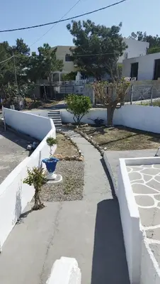 a sidewalk with two trees and a white wall at Sea Breeze Stegna in Archangelos