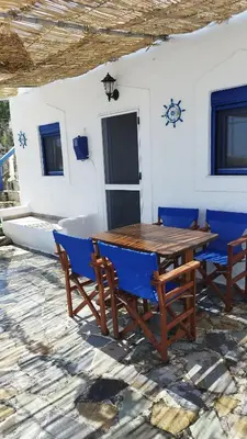 a wooden table and chairs in front of a building at Sea Breeze Stegna in Archangelos