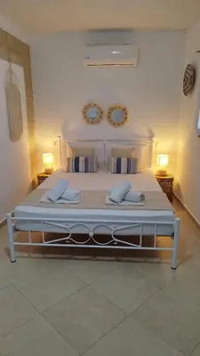 a large bed in a bedroom with two mirrors on the wall at Sea Breeze Stegna in Archangelos