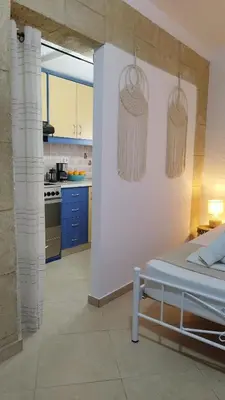 a room with a bed and a kitchen with blue cabinets at Sea Breeze Stegna in Archangelos