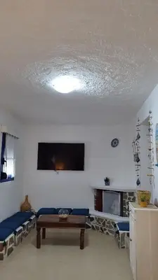 a living room with a couch and a tv on the ceiling at Sea Breeze Stegna in Archangelos