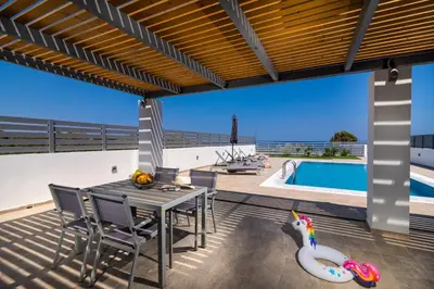 a patio with a table and chairs and a swimming pool at South Beach Villas in Gennadi
