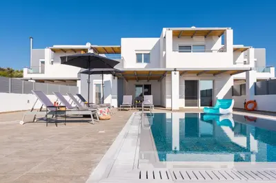 a villa with a swimming pool in front of a house at South Beach Villas in Gennadi