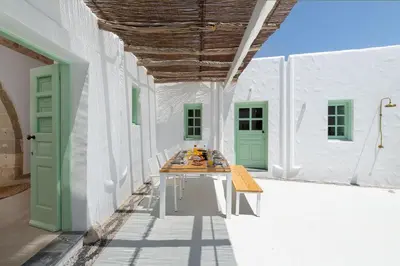 a table in a white building with green doors at Dipagio Origin Villa in Lachania